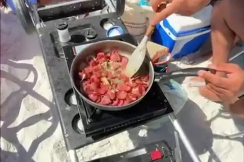 Turistas preparam linguiça acebolada na Praia do Forte, em Cabo Frio